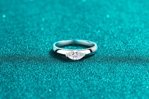 Macro shot of marquise cut moissanite silver ring on blue glitter backdrop