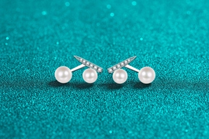 Macro detail of silver cherry earrings featuring round white pearls and sparkling moissanite