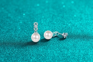 Macro detail of S925 silver pearl stud earrings featuring a sparkling infinity symbol design
