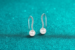 Macro detail of S925 sterling silver wavy drop earrings with moissanite and round pearl