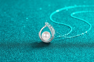 Détail d'une perle ronde blanche sertie d'un cadre goutte d'argent et de zircons