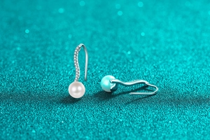 Macro shot of S925 sterling silver wave drop earrings with zircon and white pearl