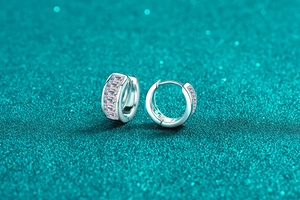 Macro shot of silver S925 earrings with rectangular moissanite stones on glitter surface