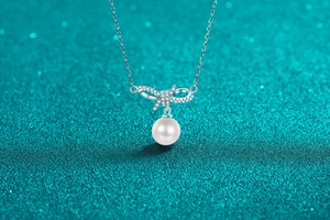 Detailed view of S925 silver bow pendant with shimmering zircons and round white pearl