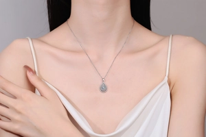 Close-up of a pear-shaped S925 silver pendant with moissanite diamonds on a model