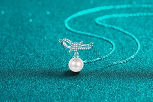 Macro shot of bow pendant with micro-pave diamonds and large white pearl on silver chain