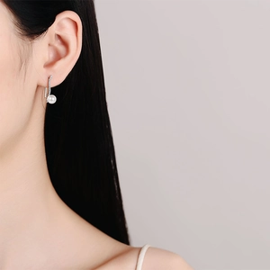 Elegant S925 silver pearl drop earrings with wavy diamond accents worn by a model