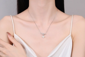 Close-up of S925 silver bow pendant necklace with Moissanite and a white pearl drop