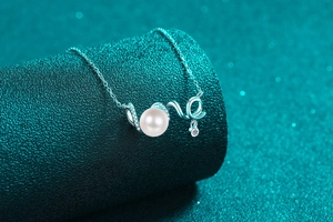 Macro shot of silver 'love' pendant with white pearl and sparkling crystals on neck display