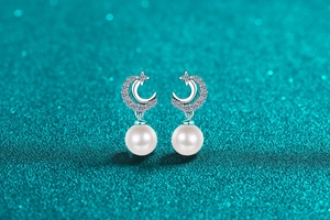 Macro shot of S925 silver star and moon pearl earrings with white cubic zirconia inlay