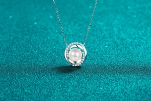 Macro shot of silver pearl necklace with double circle diamond pendant on blue texture