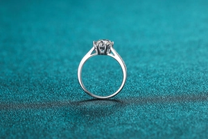 Macro detail of six-prong moissanite ring with pave diamond band on blue background