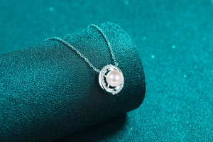 Macro view of a round pearl pendant with small crystals on a silver chain necklace