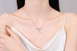 Elegante Halskette aus Sterlingsilber mit funkelndem Schleifenanhänger und runder Perle