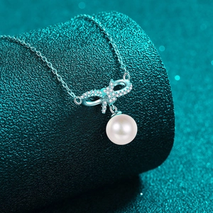S925 silver necklace with bow pendant and white pearl on a turquoise display background