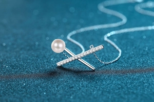 Dettaglio ravvicinato di una collana a croce in argento S925 con perla bianca e zirconi