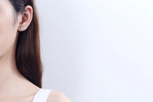 Detail of S925 silver moissanite stud earring with blue gemstone on female model
