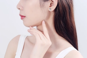 Close-up of S925 silver cat stud earrings with blue moissanite on model's ear