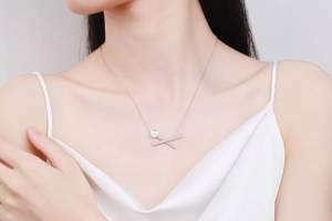 Primo piano di una collana in argento S925 con perla e pendente a croce pavé su modella