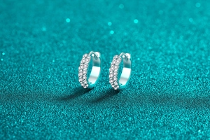 Macro shot of silver hoop earrings with spiral pavé moissanite stones on blue bokeh