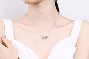 Close-up of S925 silver heart necklace with blue moissanite on female model