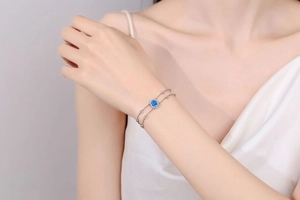 Close-up of double-chain silver bracelet with oval blue moissanite on a wrist