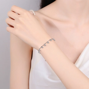 Élégant bracelet en argent 925 avec breloques en moissanite bleu clair au poignet féminin