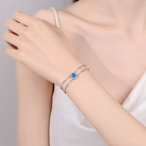 925 silver double-chain bracelet with oval blue gemstone and halo stones worn on wrist