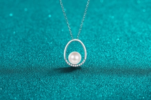 Macro shot of oval silver pendant with a white pearl and shimmering micro-set diamonds