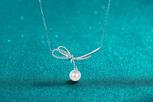 Macro view of S925 silver bow pendant with sparkling diamonds and a round white pearl
