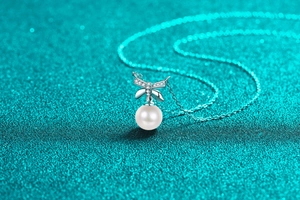 Detailed macro view of S925 silver bow pendant with moissanite and a round white pearl