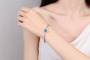 Close-up of S925 silver bracelet featuring a blue heart gemstone worn on a wrist