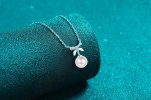 Detail of S925 silver bow pendant with sparkling moissanite and round white pearl