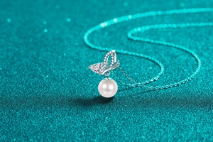 Macro shot of silver butterfly wing pendant with moissanite and round white pearl