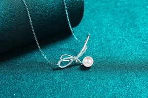 Macro view of silver bow necklace featuring sparkling zircons and a white round pearl