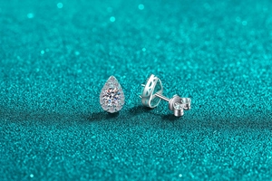 Macro detail of pear-cut moissanite stud earrings in silver halo setting with fine openwork