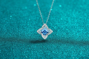 Macro view of geometric silver pendant with square blue stone and micro-pave diamonds