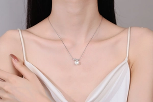 Primo piano di una collana di perle bianche su un modello con lucentezza e catena d'argento
