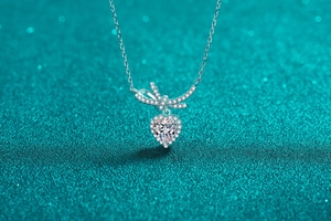 Macro detail of S925 silver heart pendant with bowknot and shimmering moissanite stones