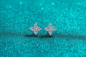 Macro shot of silver four-petal flower stud earrings with sparkling round moissanite