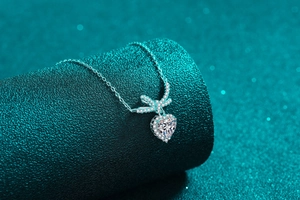 Macro shot of S925 silver heart necklace with sparkling moissanite and bow pendant detail