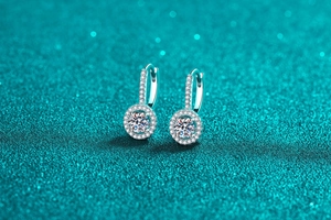 Nahaufnahme von 925 Silber Halo Moissanit Ohrringen auf blauem Glitzer Hintergrund