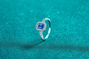 Vue macro d'une bague avec pierre bleue taille émeraude et halo de diamants étincelants