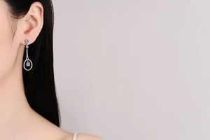 Close-up of a model wearing sparkling tennis racket silver drop earrings with zircons
