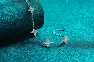Macro view of S925 silver bracelet with sparkling zircon flower charms on a teal stand