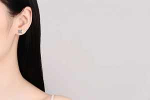 Detail of star-shaped S925 silver stud earring with blue moissanite stones on ear
