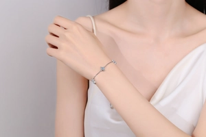 Close-up of a silver bracelet with blue pavé clover charms worn on a woman's wrist