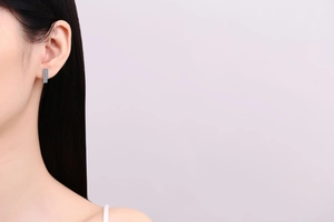 Close-up of a model wearing rectangular blue pavé-set moissanite silver hoop earrings