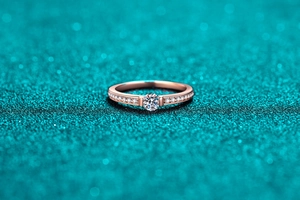 Macro view of rose gold ring featuring a brilliant moissanite center and side diamonds