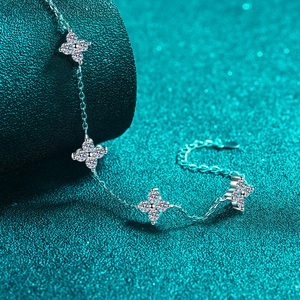 S925 sterling silver bracelet with sparkling flower-shaped moissanite charms on green background